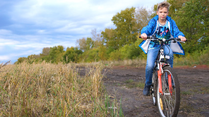 Obraz premium Teenager riding a bike, doing sports in the fresh air. Travel and active entertainment. Moments of happy childhood
