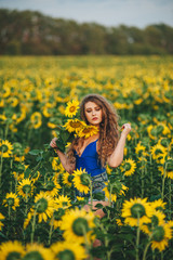 Obraz na płótnie Canvas Young beautiful woman in a dress among blooming sunflowers. Agro-culture.