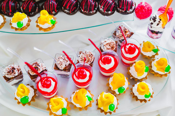 Delicious and tasty dessert table with cupcakes shots at reception closeup