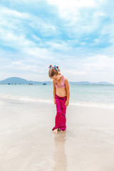 Little beautiful girl dressed in swimsuit as a mermaid stay on the seashore