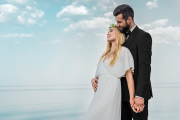 Fototapeta na wymiar wedding couple in suit and white dress hugging on beach
