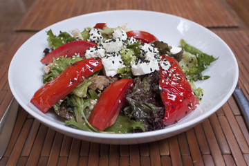 Vegetable salad with tomatoes, baked bell pepper, cheese and pieces of turkey meat