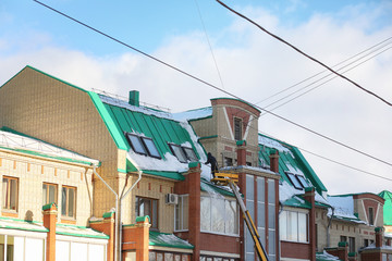 The cleaning service cleans the snow from the roof of the house.