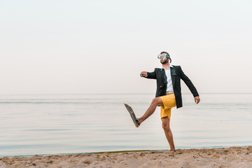 man in black jacket and shorts walking with swimming mask and flippers on sandy beach © LIGHTFIELD STUDIOS