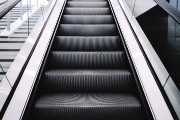 Escalators in big modern area. No people around. Grey tones interior design with shiny glass....