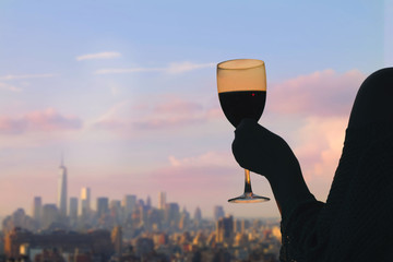 Female hand with glass of wine on Manhattan background. New York city.  Service on the roof of the restaurant

