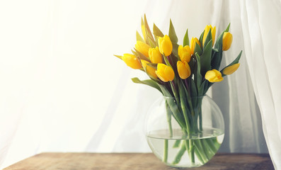 A bouquet of red tulips in a vase on the windowsill. A gift for 