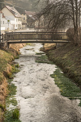 Fototapeta na wymiar Holzbrücke über Fluss in ländlicher Umgebung