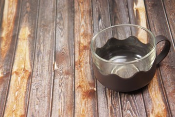 An empty cup that made from clear glass and plastic handle on a wooden background