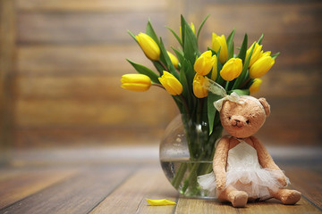 A bouquet of yellow tulips in a vase on the floor. A gift to a w