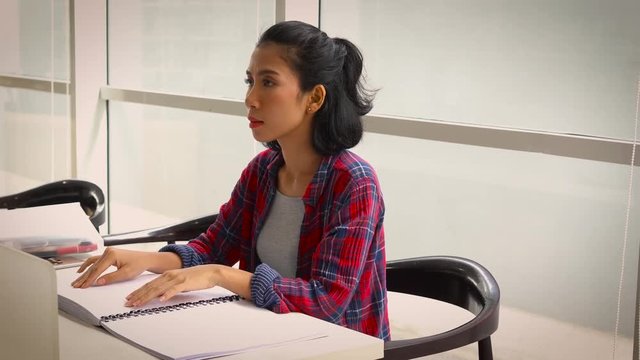 Young Asian blind woman reading a braille book while sitting in the library. Shot in 4k resolution