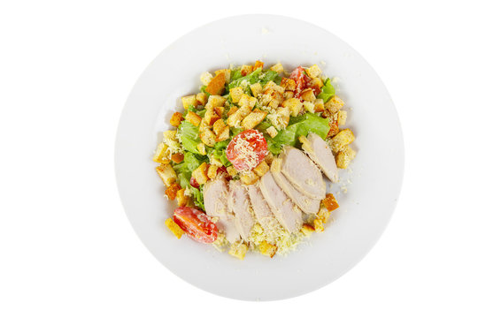 Caesar salad with slices of chicken breast, rusks, cherry tomato, lettuce, cheese on plate, white isolated background, view from above, for the menu, restaurant, bar, cafe