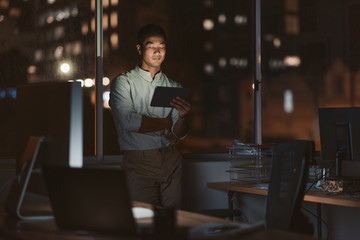 Fototapeta premium Asian businessman working late in his office with a tablet