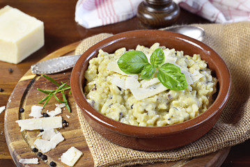 Delicious risotto dish in a brown bowl, with mushrooms and parmesan cheese. Risotto a la milanese, close up shot.