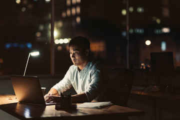 Young Asian businessman working late at night at his desk