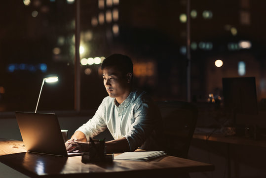 Young Asian Businessman Working Late At Night At His Desk