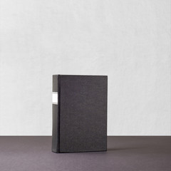 Black book with white frame on spine standing on dark surface