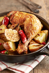 Oven-baked chicken with vegetables and fresh herbs. Homemade food. Symbolic image. Concept for a tasty and hearty dish. Rustic wooden background. 