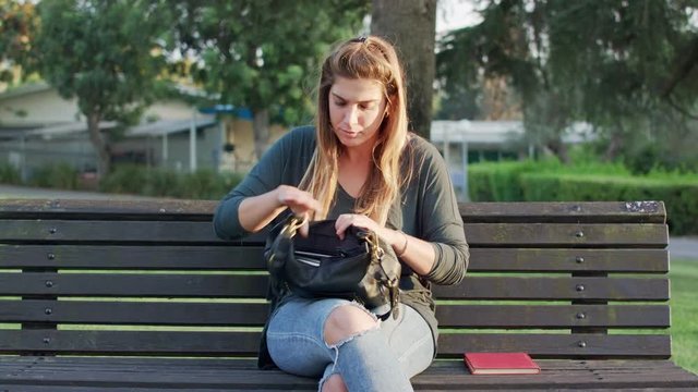 Young woman sitting on a bench, recieving a message and looking around