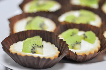 Tart with kiwi fruit and cream close up on cupcake paper, selective focus