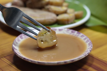  Grilled banana with dipping sauce on wooden table.