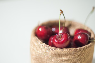 Sweet cherries in jute sack on isolated white background