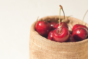 Sweet cherries in jute sack on isolated white background