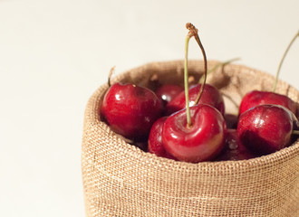 Sweet cherries in jute sack on isolated white background