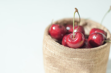 Sweet cherries in jute sack on isolated white background