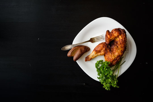 baked chicken on a plate, on a black background