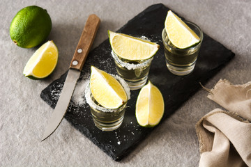 Mexican Gold tequila with lime and salt on gray background