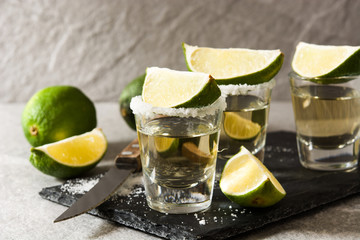 Mexican Gold tequila with lime and salt on gray background