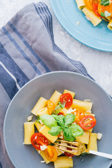 Italian fresh salad of pasta made with calamarata pasta,garlic,parmesan,and olive oil,with freh basil, top view natural light.