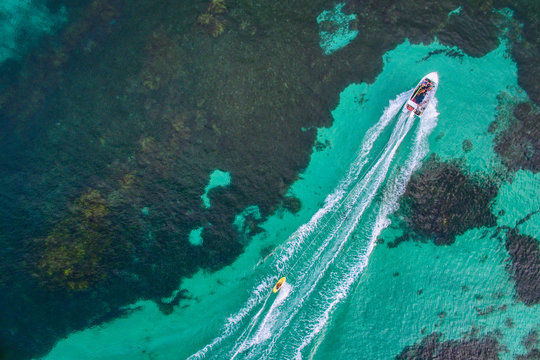 Aerial view of waterskier being towed by a speedboat over crystal clear waters in Western Australia