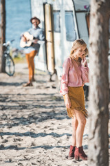 selective focus of smiling girl and man playing guitar near trailer behind