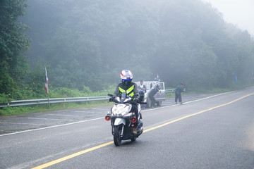 Obraz premium Tajska policja prowadzi motocykl. Do Doi Inthanon, Chiang Mai - Tajlandia. Na drodze w gęstej mgle i mrozie.