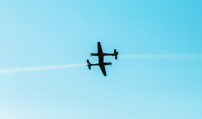 Silhouette of two airplanes crossing each other's path almost hitting. Planes making risky aerial...
