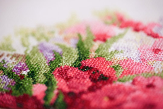 Close up of a fragment of a cross-stitch embroidery with flowers.