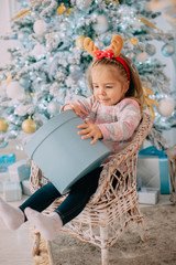 girl unpacks gift on background of Christmas tree