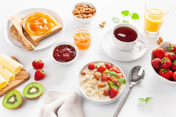 healthy breakfast with oatmeal porridge, strawberry, nuts, toast, jam and tea