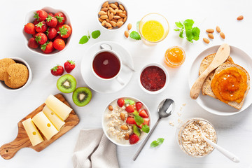 healthy breakfast with oatmeal porridge, strawberry, nuts, toast, jam and tea. Top view