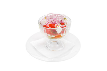 Salad of vegetables in a glass bowl of vegetables, tomatoes, onions, feta, cheese, salakis, pesto sauce, basil, spices, on a plate with a napkin, white isolated background Side view. For the menu