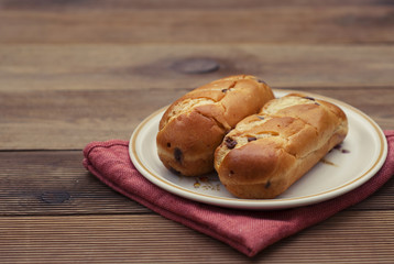 Traditional Buns with chocolate chips, breakfast or snack, rustic wood table.
