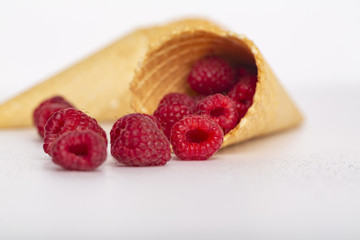 Ice cream or delicious dessert made from fresh raspberry berries on white background. Raspberry in a waffle cone. Summer, freshness, and the concept of the sweet menu.