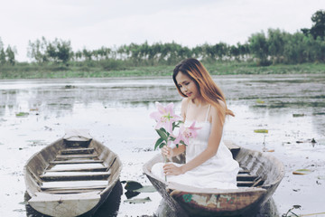  woman holding a lilies sits on a boat in a swamp
