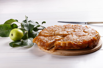 Apple Tarte Tatin - classic French upside-down tart. Whole fruit pie on white table. Rustic style.