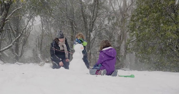 Family build a snowman as the snow falls in Australia