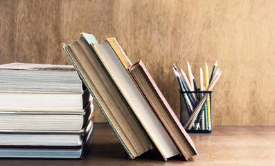 Old hardback and textbook stacked on the wooden table. The concept of intelligence comes from education. Selective focused on the textbook.