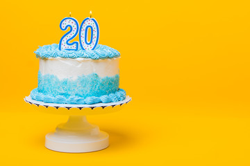 White cake with blue decorations and 20 candle on top