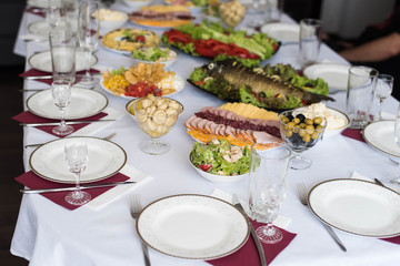 Glasses goblets on white table. Room with table serving fruits and dishes and meal.